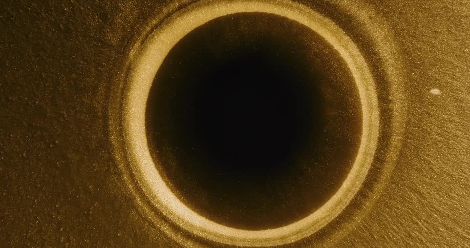 Abstract footage of a sphere forming in gold liquid