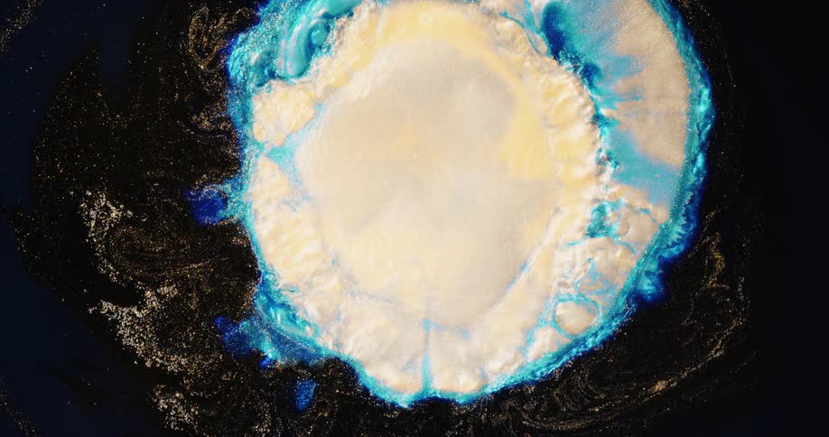 A blue burst of colored light explodes in a round shape as white grows in from the center and shrinks into an organic object