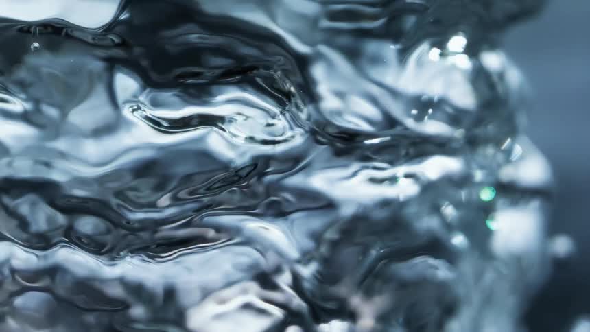 Light shines on a bubble underwater as it grows and ripples and small bubble spheres emerge