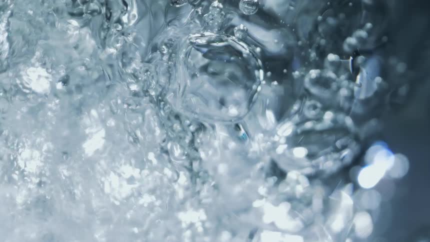 Stream of air create a stream of ripples and bubbles inside a tank filled with water