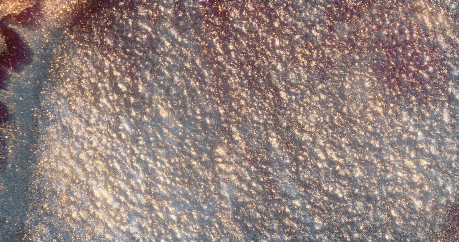 A foam forms at the surface of a shimmery liquid