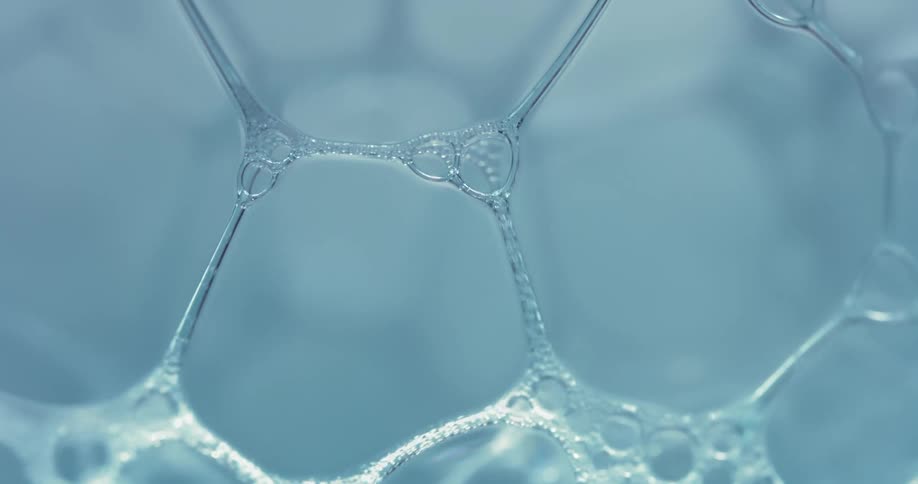 Soap bubbles form a honeycomb pattern on the surface of water
