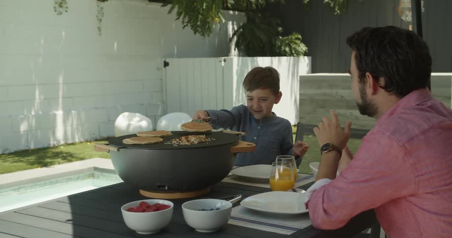A child serves himself some pancakes outside