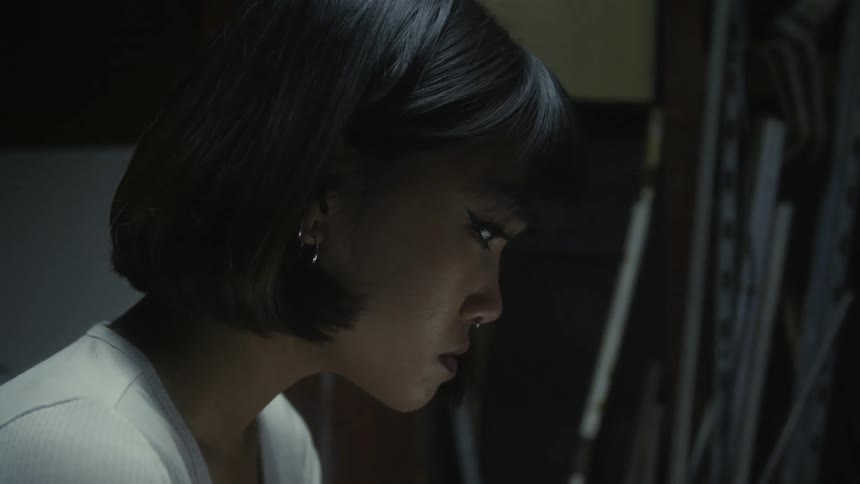 Profile of a young beautiful woman with short hair with a nose ring sitting in a dimly lit room