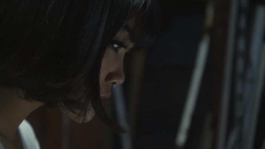 A young woman in a dark room looks down