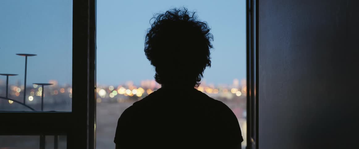 There is a man that is looking outside the window in the day time