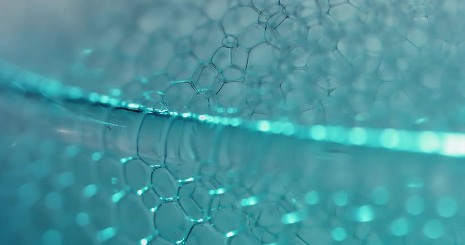 A thin layer of blue air bubbles rise up over the edge of a container