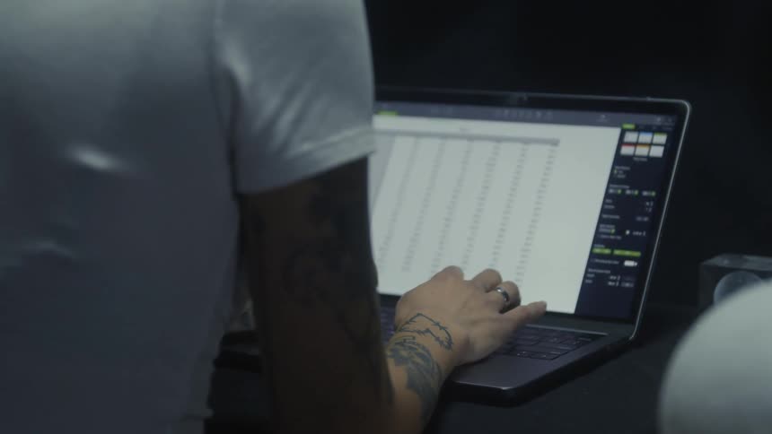 Woman with tattoo and white shirt uses laptop