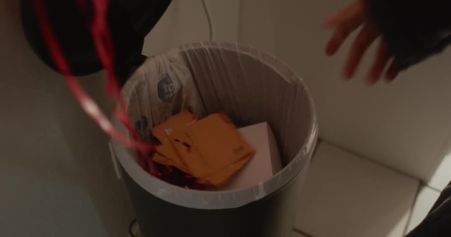 A person throws garbage in a garbage can at home