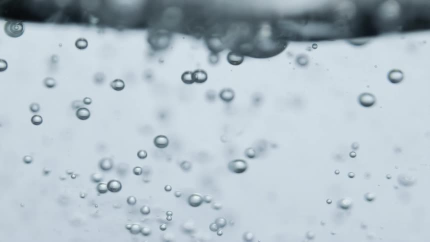 Small bubbles rise to the turbulent surface in water