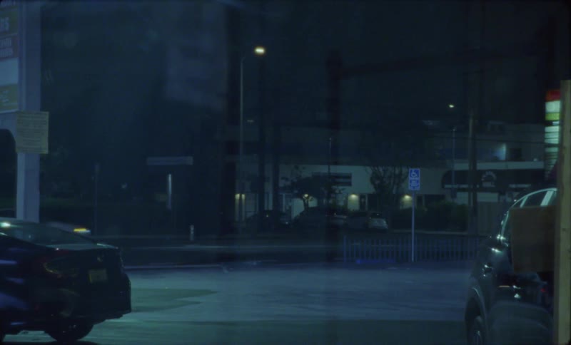 Car drives by a parking lot on a small town at night