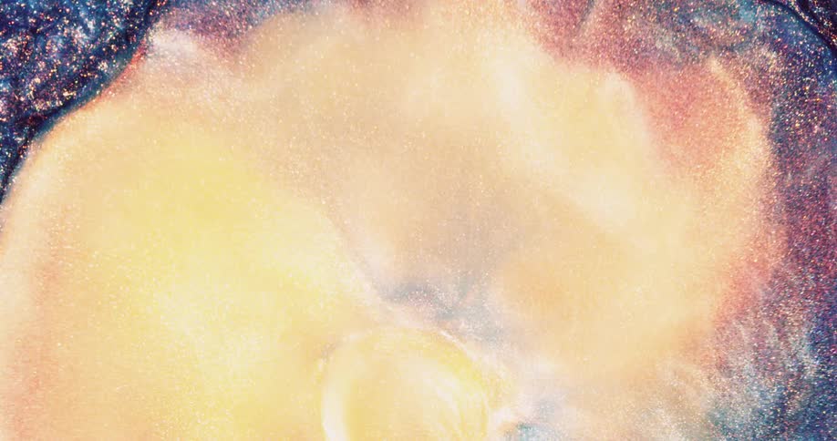 An organic multicolored substance is sparkling as it bubbles as a yellow orb erupts and fills the area and blends in with the other colors when it shrinks