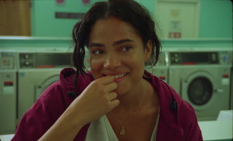 A young woman is sitting in a laundry mat as she smiles and laughs