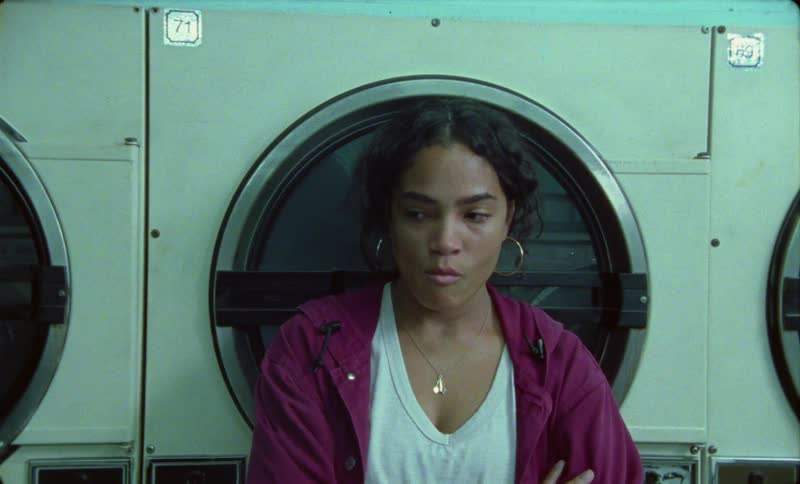 Bored woman waiting next to a washing machine inside a laundromat
