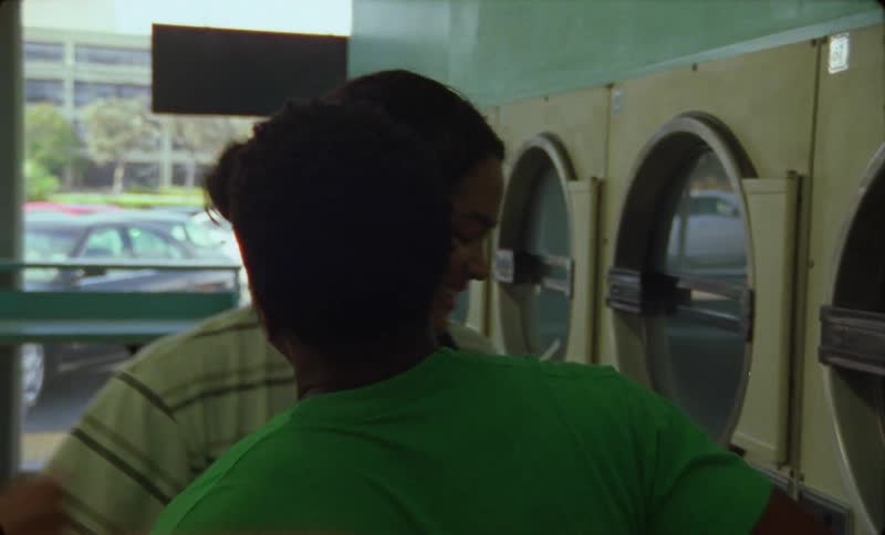 Young happy woman hugs a friend inside a laundromat in the city