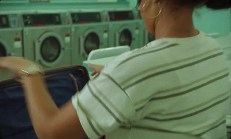 A woman is washing clothes in the laundromat