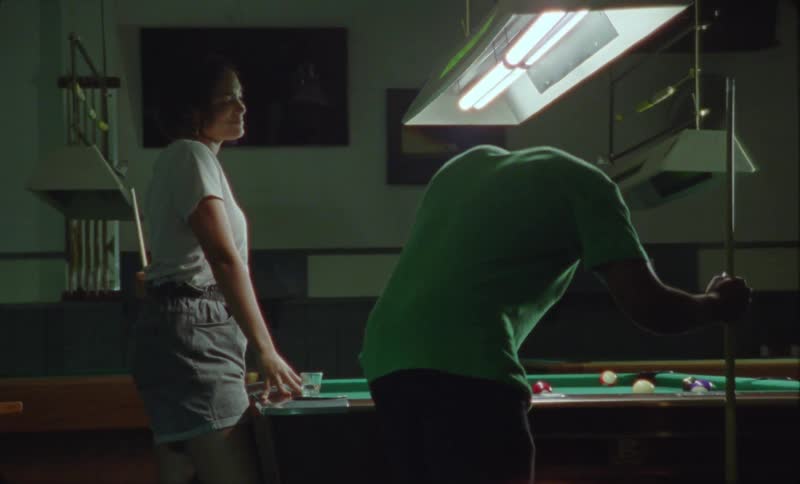 A man and woman playing pool in a billiard room