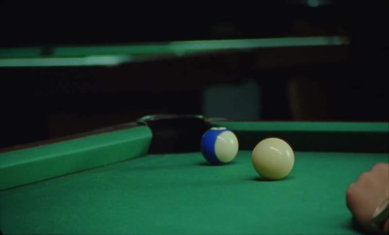 Someone is playing pool inside of a bar and hitting the balls