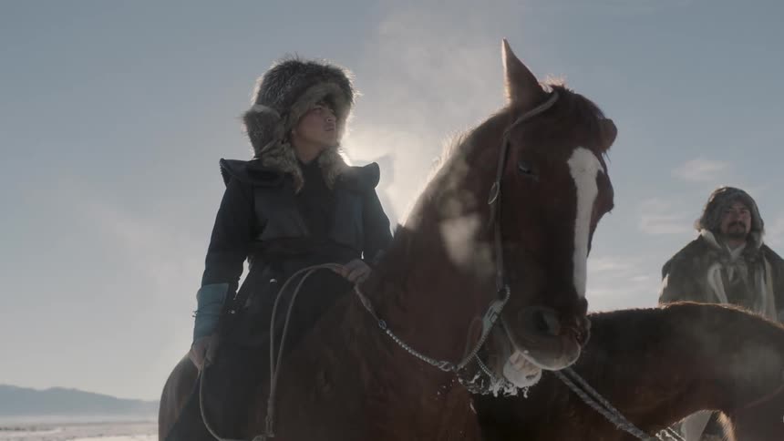 Three riders on horseback look into the distance