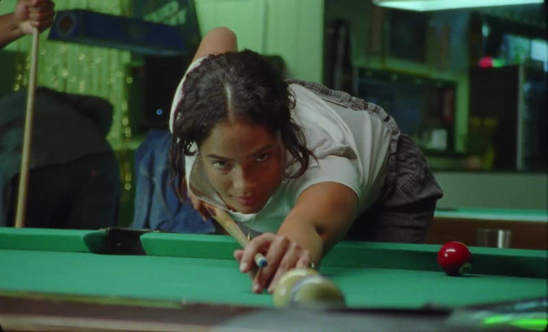 A young woman and man are playing pool against each other