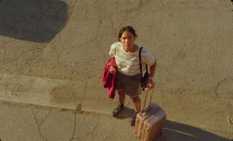 Young woman standing on the sidewalk carrying luggage angrily talking to herself