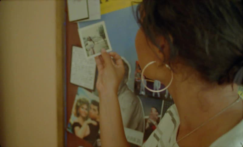 There is a young woman that is looking at pictures on the wall