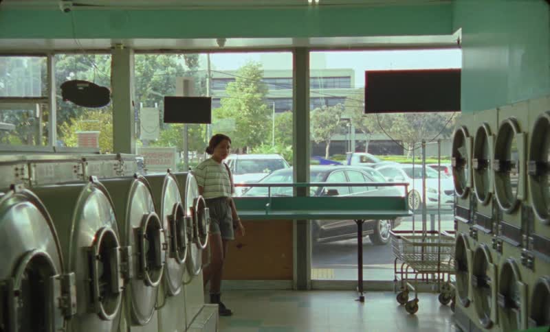 Woman walks into laundromat and faces man putting clothes into dryer