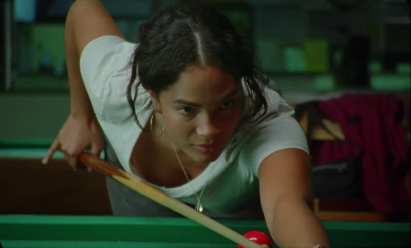 A young hispanic woman is playing pool inside