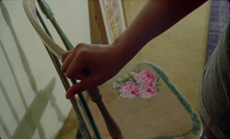 Person wearing shorts holds top of chair that is decorated with a flower