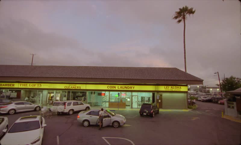A woman gets out of a car in front of a strip mall