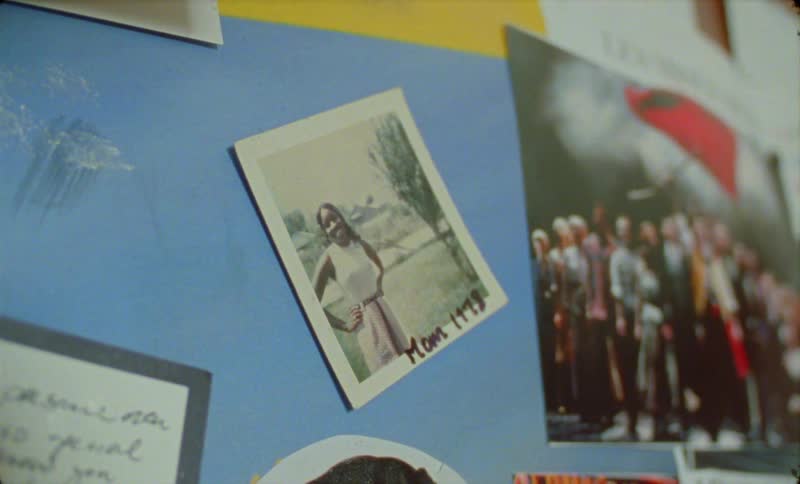 There is a black woman that is putting pictures on a wall
