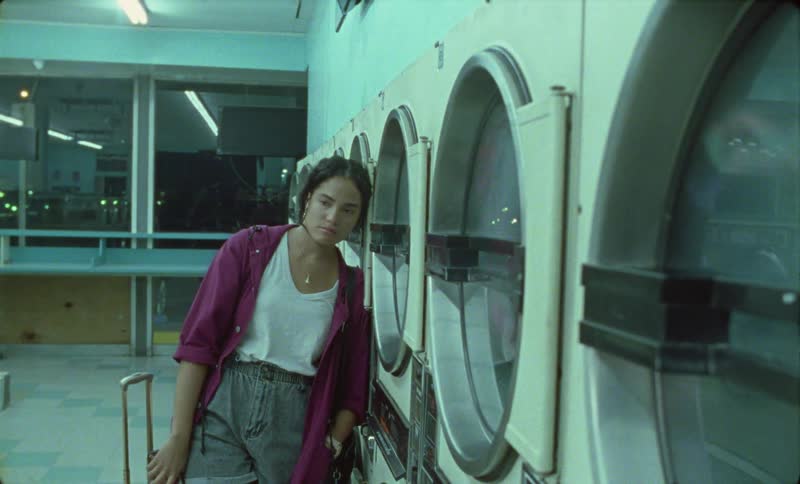 There is a young woman washing clothes at the laundromat