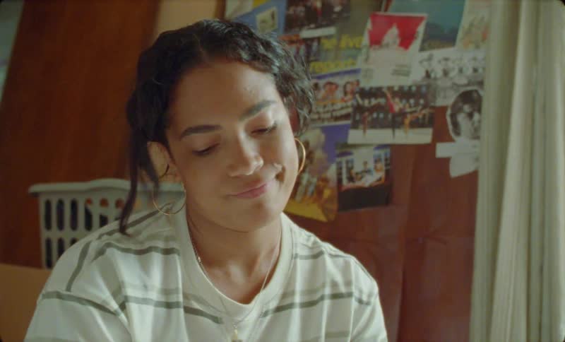 A teenage girl is sitting in her room talking to someone off camera