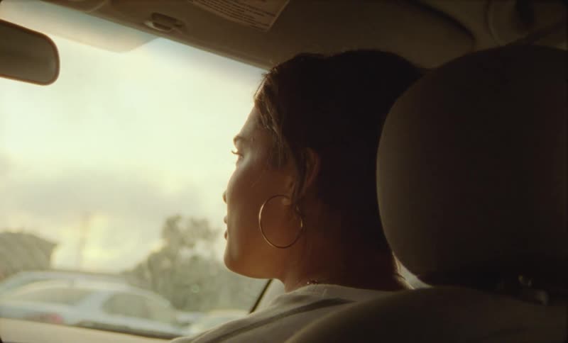 There is a young hispanic woman sitting inside of a car
