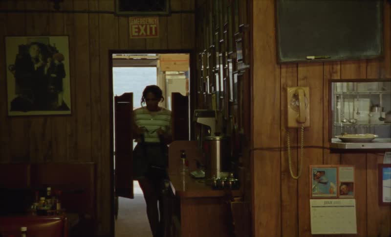 A woman walking through a door in a diner with her purse