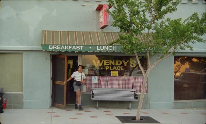 A woman exiting a restaurant onto a city street