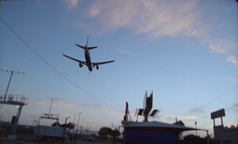A jet airplane flies low over a busy street as it comes in for a landing