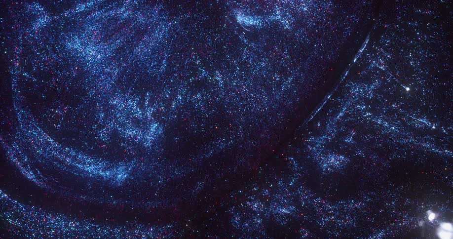 Blue and purple pinpoints of light glitter like stars in the darkness and a bubble orb emerges and takes them into a vortex