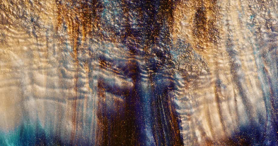 Waves of glittery shiny colorful golden liquid ink flowing up in waves and ripples