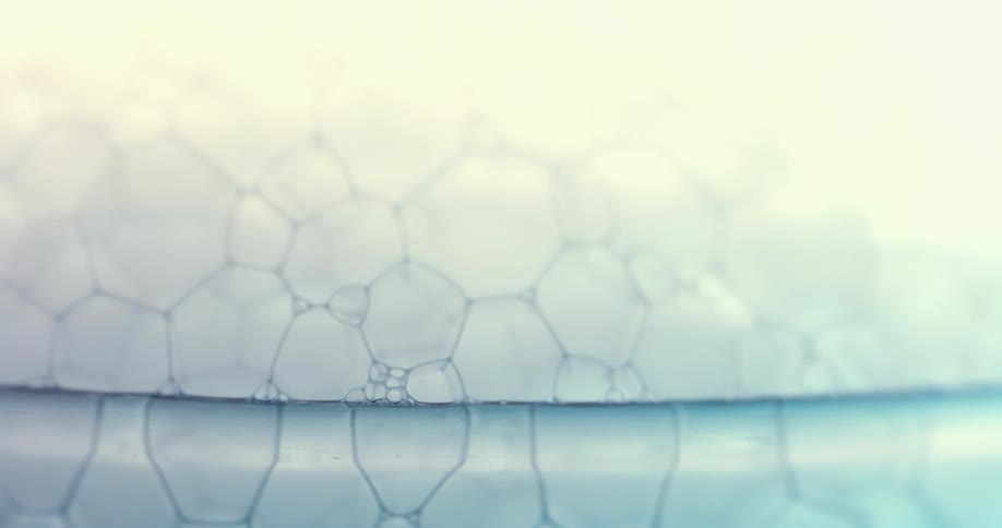 Close up of soap bubbles overflowing the rim of a glass container