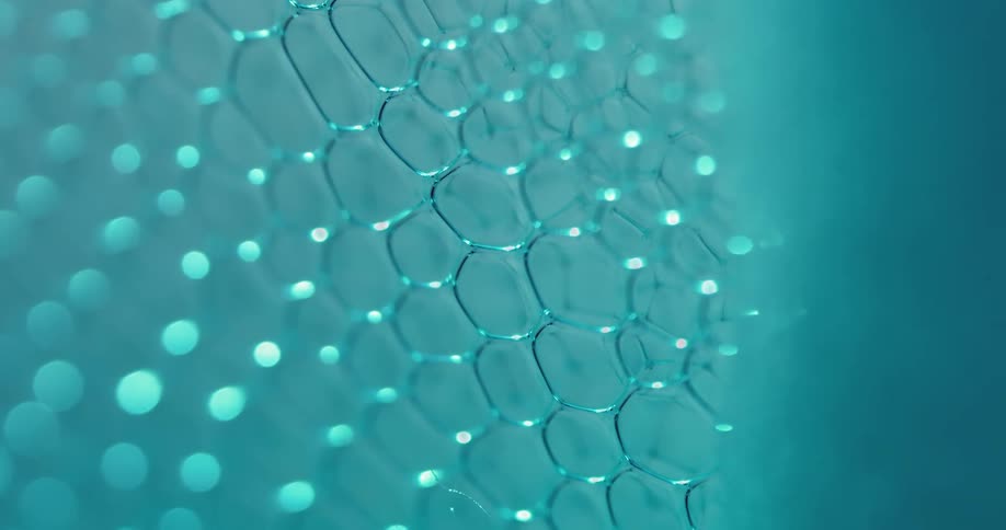 Close up of a tight group of small blue soap bubbles moving while popping