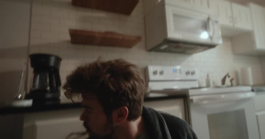 A white man is inside of his kitchen and looks like he is scared