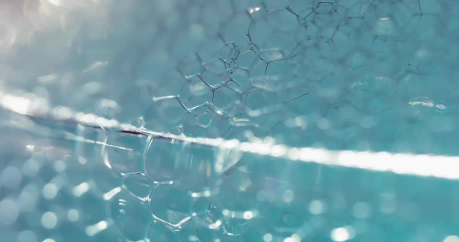 Close up of soap bubbles rising and going over the rim of a glass container