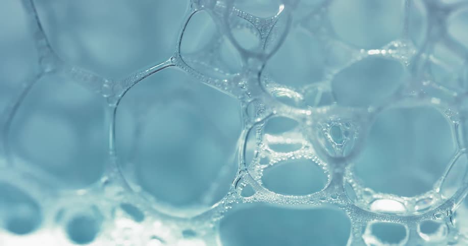 A clear bubble substance reflects as it moves over a light blue area