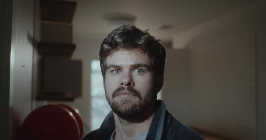 A young white man is standing indoors inside of his house