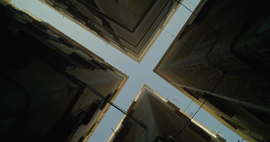 Looking straight up at the cross shaped clear sky between buildings at an intersection