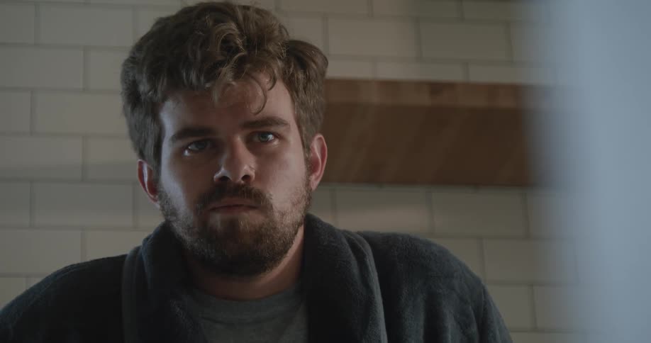 A man is sitting in a room staring straight ahead without talking
