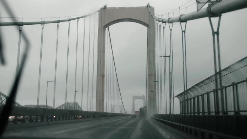 A car driving over a cable bridge during a rainstorm