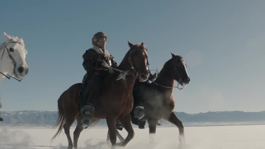 People are riding horses in the snow on a cloudy day