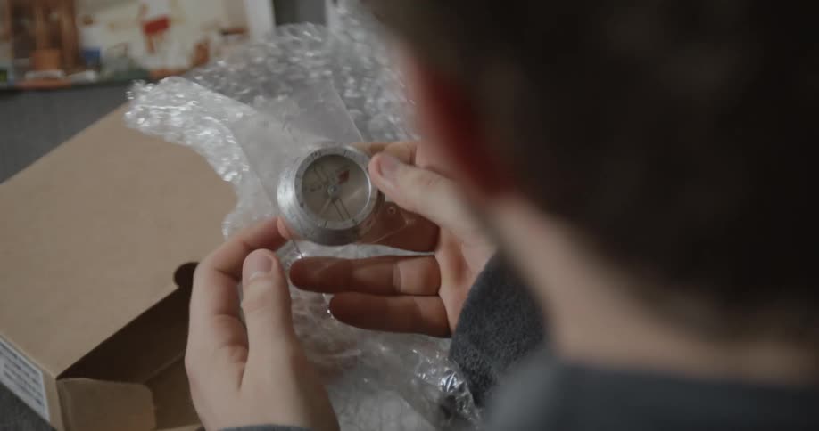 A man opens a box and removes a gauge from the bubble wrap